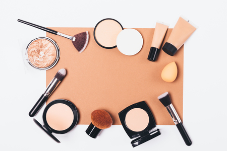 Cosmetics for correction of facial skin imperfections and accessories for its application on white table, top view. Flat lay frame of makeup products and brushes with sponges.の写真素材