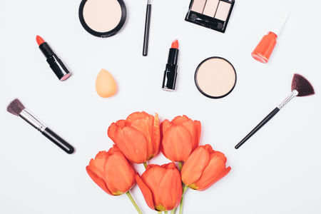 Festive flat lay composition of bouquet of flowers and women's makeup around, top view on white background.の写真素材