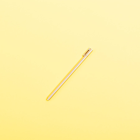 Top view golden ballpoint pen with cap on yellow background, flat lay.の写真素材