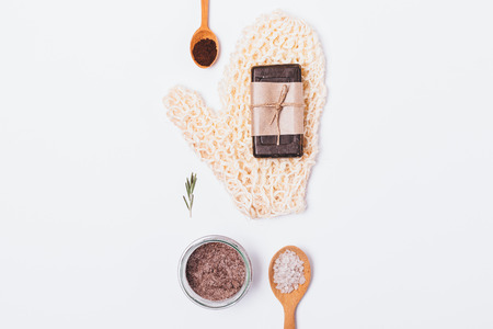 Natural beauty products and accessories for cleansing and exfoliating dead skin cells. Rough washcloth, soap, coffee scrub with sea salt and rosemary oil, flat lay on white background.の写真素材
