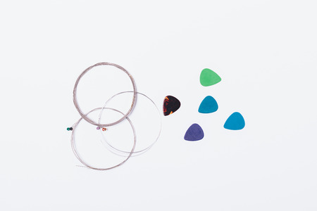New guitar strings and set of picks on white background, flat lay.