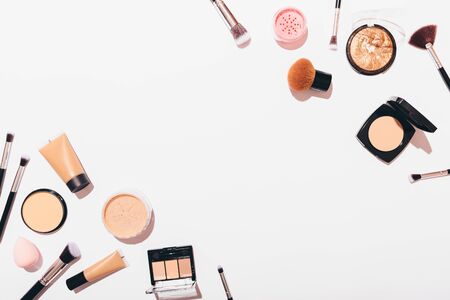 Flat lay frame of makeup products on white background with an empty space in center.の写真素材