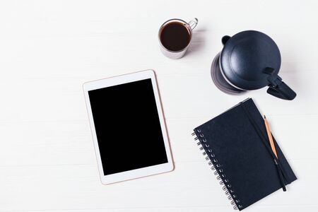 Tablet computer with blank screen near paper notepad, moka pot coffee maker and cup of espresso on white table, flat layの写真素材