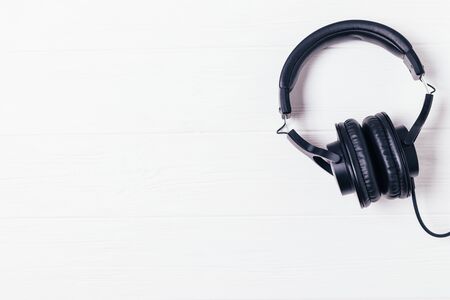 Black headphones on white wooden background with copy space, flat layの写真素材