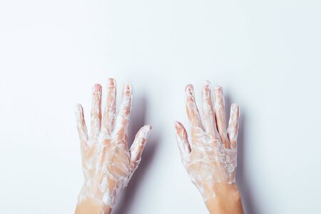 Woman's hands in soap suds, overhead view on white background.の写真素材