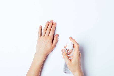 Overhead view woman's hands applying alcohol sanitizing spray on skin to protect from microbes and viruses.の写真素材