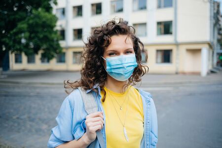 Responsible young woman wearing medical protective mask while walking in public place in the city on summer day.の写真素材