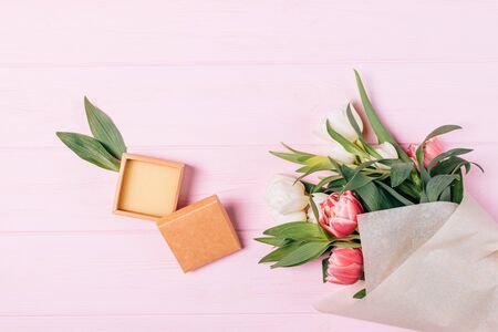 Flat lay composition small open empty gift box next to bouquet of fresh flowers on pink wooden background.の写真素材