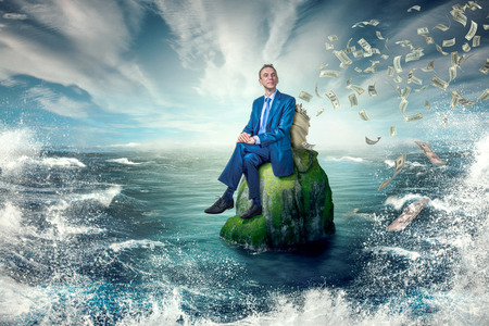Calm, smiling man sitting on a rock.Money down the drain.の写真素材