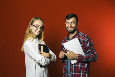 Two teenager students looking to camera holding books on red backgroundの写真素材