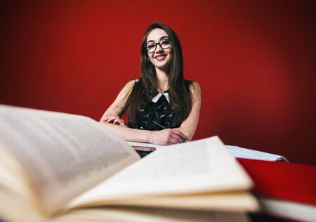 Young attractive brunette happy girl in glasses studying with book