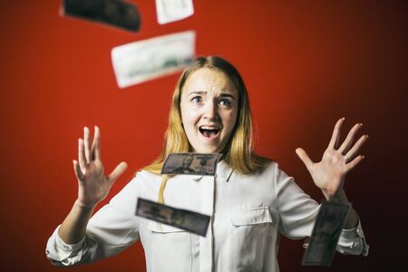Attractive blonde woman with falling dollars banknotes red background, jackpot conceptの写真素材