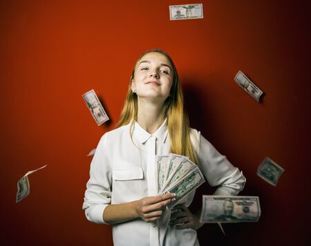 Attractive blonde woman with falling dollars banknotes red background, jackpot concept