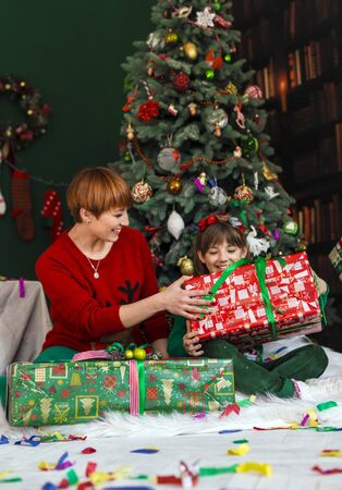 Mother with her happy kids have got gift boxes under Christmas treeの写真素材