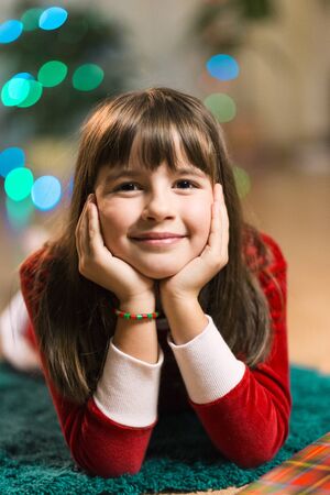 portrait of happy smiling girl lying on blue carpetの写真素材