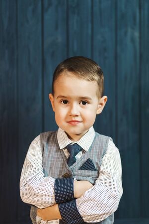Portrait of kid boy wears elegant suit with tie before blue wood wallの写真素材