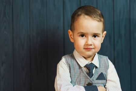 Portrait of kid boy wears elegant suit with tie before blue wood wallの写真素材