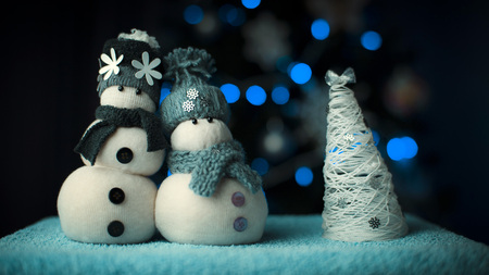 Couple of handmade snowmans figures with christmas tree on bokeh light backgroundの写真素材