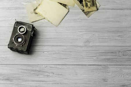 Studio shot of old vintage photo camera with pictures on wooden backgroundの写真素材