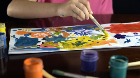 Kid girl painting with brush and gouache ink on white paper, happy and fun colorful youth drawing,...
