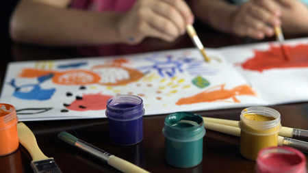 Kid girl painting with brush and gouache ink on white paper, happy and fun colorful youth drawing, childhood conceptの写真素材