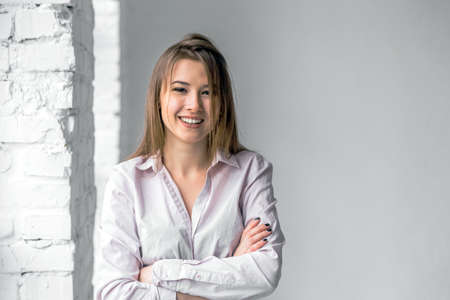 Portrait of young beautiful girl wears white scirt on white bricks studio backgroundの写真素材