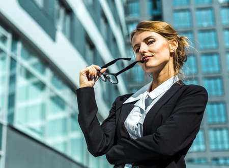 Young blonde caucasian businesswoman wears glasses, white blouse and a black jacket before the...