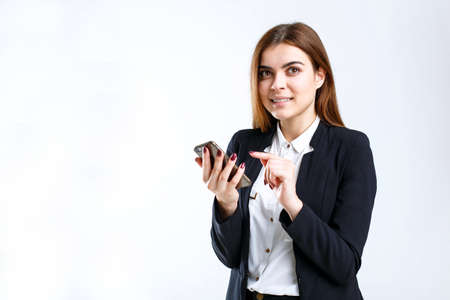 Young cheerful smiling businesswoman holds smartphone in hands on white isolated background with copyspaceの写真素材