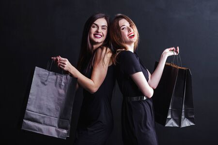 Elegant brunette womans wears black dress holding black shopping bags, black friday conceptの写真素材