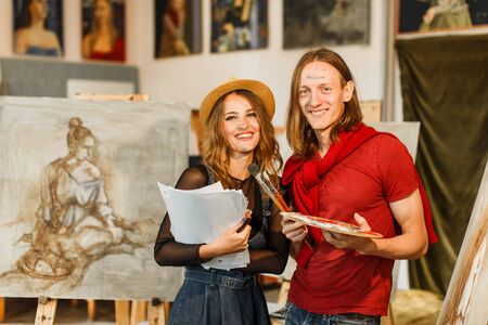 Young artists couple smiles near the picture in the studio