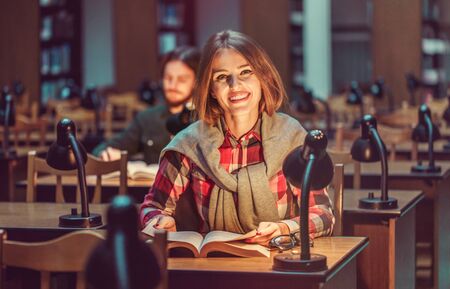 Portrait of two successful students casual stylish, boy and girl in library reading hall, evening time, education conceptの写真素材