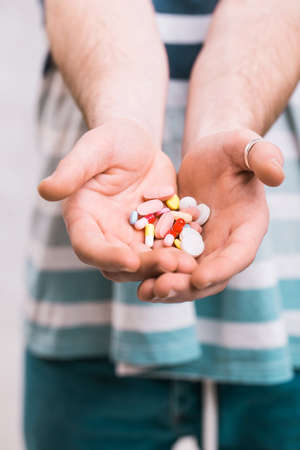 Closeup of a man holding colorful pills in his right handの写真素材