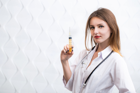 Female caucasian doctor squirting liquid, pretty slim woman holding a squirt, closeupの写真素材