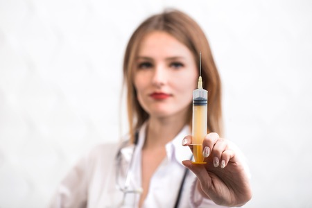 Female caucasian doctor squirting liquid, pretty slim woman holding a squirt, closeupの写真素材