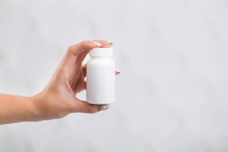 Slim young girl in white doctors smock holds bottle with drugs, indoor isolated shotの写真素材