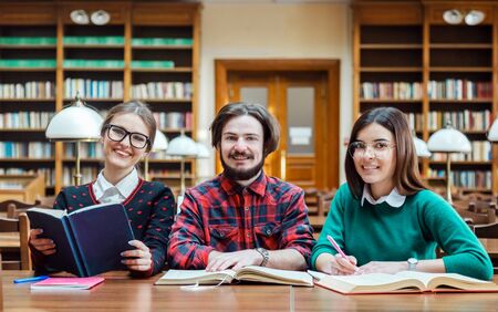 Engaged students checking information in different booksources, indoor shot in college library