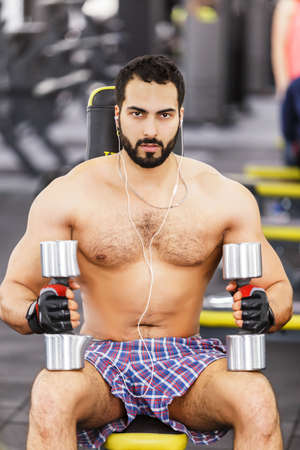 Topless bearded man holds metal dumbbells in the gymの写真素材