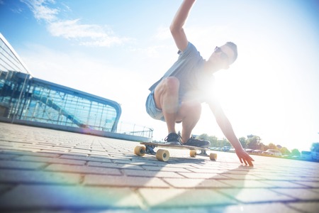 Skateboarder rides longboard on brick ground before sunset, sunny dayの写真素材