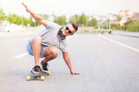 Skateboarder in sunglasses rides longboard on asphalt road in the city, low position trick rideの写真素材