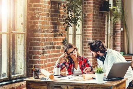 Two ambitious architects discussing construction project in loft modern office, they using laptopの写真素材