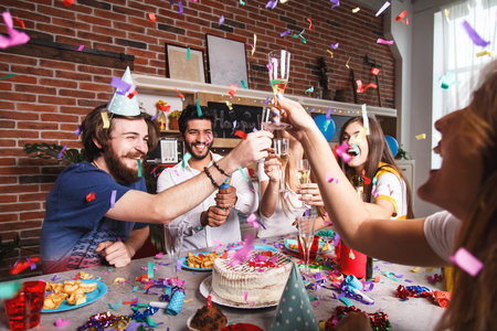 Group of multicultural friends enjoying party, eating snacks and throwing confetti. Friends having fun at the kitchenの写真素材