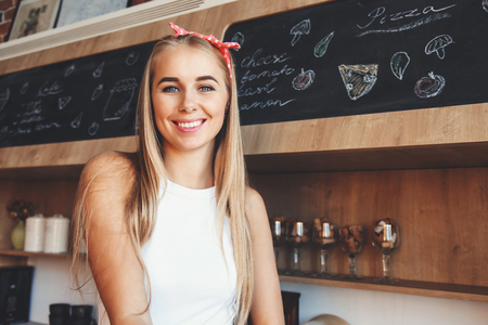 Beautiful woman standing happy and smiling in the modern kitchen, she preparing her morning coffeeの写真素材