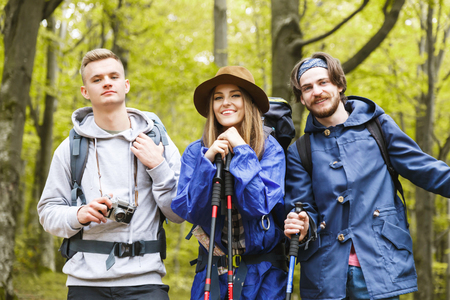 Aspirational lifestyle image of happy young people hiking, thrtee young hiker friends with backpacks...