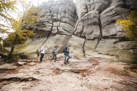Three young travellers with backpacks hiking in the beautiful rocks, travelling conceptの写真素材