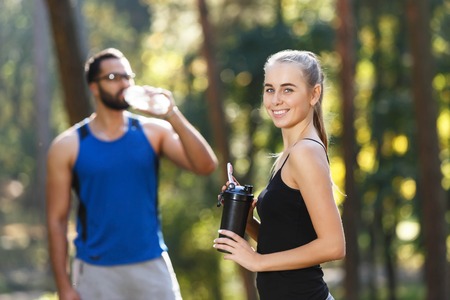 Young sportish couple on the morning running, they are tired and drinking water