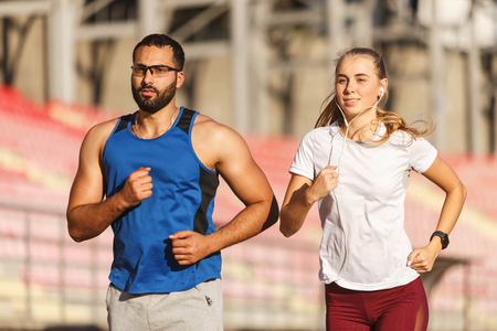 Happy athletic people jogging at the football stadium outdoorの写真素材