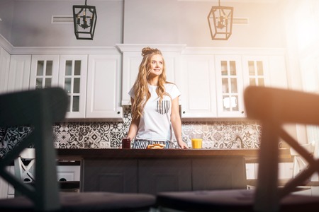 Young woman standing near the table in the kitchenの写真素材