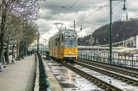 BUDAPEST, HUNGARY - 24 August, 2018: Retro yellow tram in Budapest in Hungary riding on the rails in a on a cloudy spring dayのeditorial素材