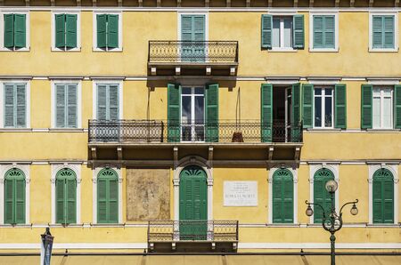 VERONA, ITALY - AUGUST 26, 2018: Symmetrical view on a typical picturesque fasad of house in Verona, with colored shutters on the windows and forged balconiesのeditorial素材