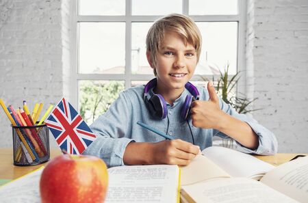 Portrait of successful teenage schoolboy sitting in the classrooom
